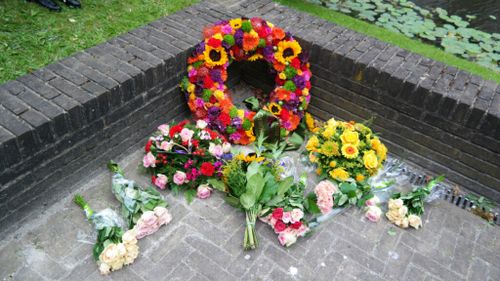 Bloemenkrans, en bloemen die eromheen liggen, ter herdenking van het slavernijverleden. Deze waren in 2022 gelegt.
